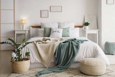 Rahat yataklı, komodinli ve çiçekli aydınlık yatak odasının içi.