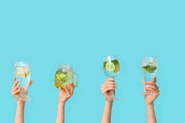 Mavi arka planda lezzetli mojito bardaklarıyla kadın elleri.