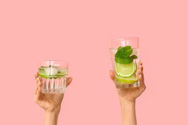 Pembe arka planda lezzetli mojito bardakları olan kadın elleri.