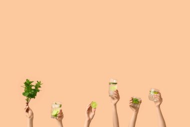 Bej arka planda mojito bardakları, limon ve nane şekerli kadın elleri.