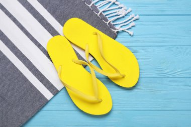 Şık terlikleri ve mavi ahşap arka planda plaj havlusu olan kompozisyon