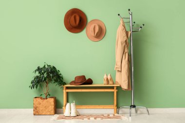 Koridorun içinde şık şapkalar, bank ve askılar var.