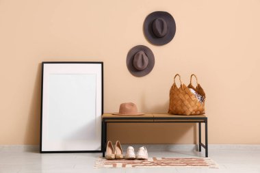 Koridorun içinde şık şapkalar, bank ve boş çerçeve var.