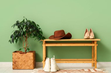 Şık keçeli şapka, koridordaki yeşil duvarın yanındaki bankta ayakkabılar.