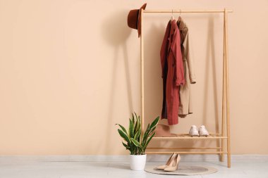 Keçeli şapka, ayakkabı ve bej duvarın yanında bitki örtüsü.