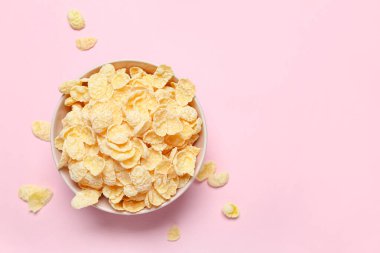 Pembe arka planda lezzetli mısır gevrekleri olan kase, yakın plan.