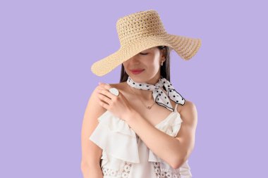 Leylak arkaplanda yaz şapkalı şık bir genç kadın.