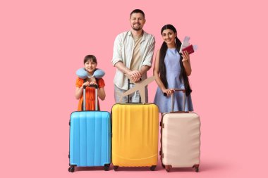 Bavullu turist ailesi ve pembe arka planda kağıt uçaklar.