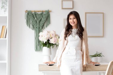 Masasında şakayık çiçekleri olan genç bir kadın.