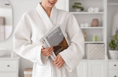 Waffle bornozlu, evde dergileri olan genç bir kadın.