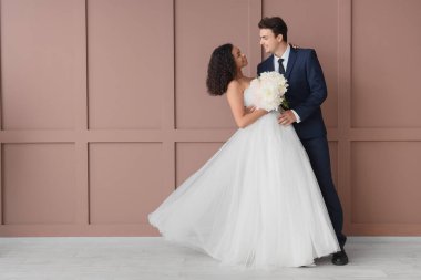 Genç bir çift kahverengi duvarın yanında.