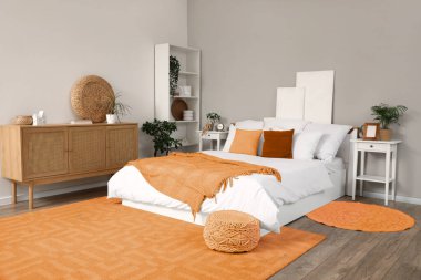 Yatağı, komodinleri ve çekmeceleri olan şık bir yatak odası.