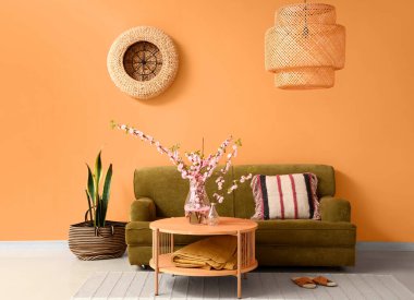 İçinde yeşil kanepe ve kahve masasında çiçek açan sakura dalları olan rahat bir oturma odası.