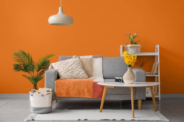 Yastıklı gri kanepe ve çiçekli narsis çiçekleri şık oturma odasının içindeki sehpanın üstünde.