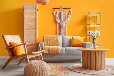 Kahve masasında gri kanepe, koltuk ve kasımpatı çiçekleri olan şık bir oturma odası.