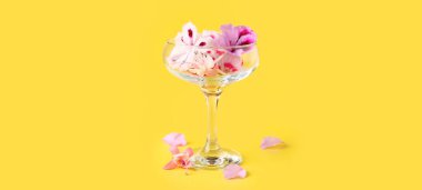 Sarı arka planda farklı güzel, yenilebilir çiçekli cam.