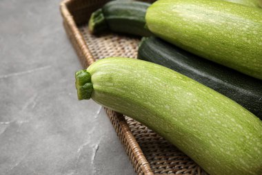 Gri arkaplanlı taze kabaklı hasır tepsi.