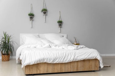 Çift kişilik yataklı, beyaz yastıklı ve çiçekli hafif yatak odasının içi.