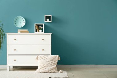 Renkli duvarın yanında kitap, dekor ve yastıklı çekmeceler.