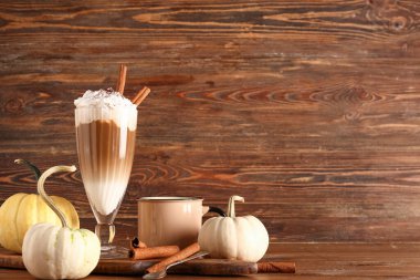 Tarçınlı balkabaklı latte ve ahşap arka planda bir fincan espresso.