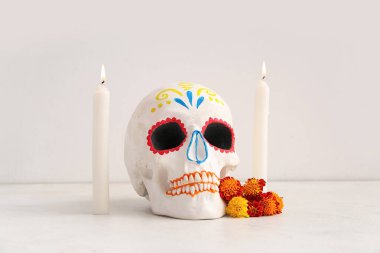 Kadife çiçekli mumlar ve beyaz arka planda boyalı kafatası. Meksika Ölüler Günü 'nün Kutlaması (El Dia de Muertos)