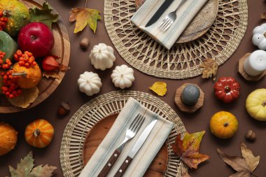 Kahverengi arkaplanda sonbahar dekoru ve mumlarla süslü masa ayarları