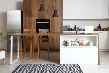 Modern mutfak, beyaz mobilyalar ve ahşap ada masası.