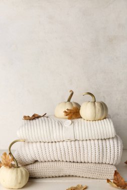 Yığınla örgü kıyafet, balkabağı ve sonbahar yaprakları açık ahşap masada.