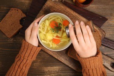 Ahşap zemin üzerinde lezzetli tavuk çorbası olan bir kadın kaseye baharat ekliyor.