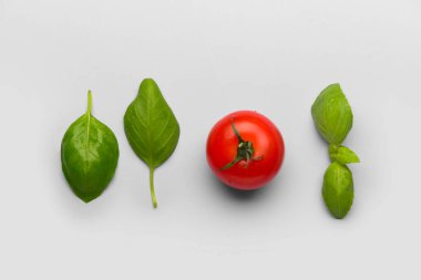 Taze yeşil fesleğen ve gri arka planda domates.