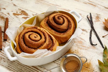 Beyaz ahşap arka planda lezzetli tarçınlı börekler pişirmek