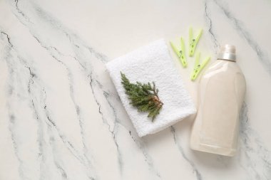 Temiz havlu, mandallar ve beyaz mermer arka planda kozalaklı bir şişe deterjan.