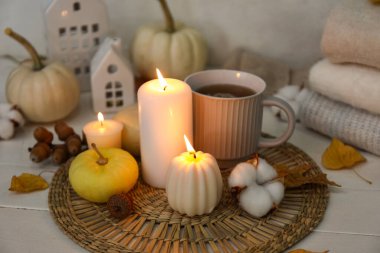 Yanan mumlar, bir fincan çay ve açık ahşap masada güzel bir sonbahar dekoru.