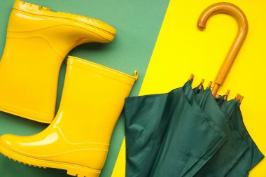 Renkli arka planda yeşil renkli şemsiye ve sarı çizmeler.