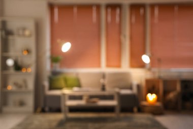 Gri kanepeli, yanan mumları ve parlayan lambaları olan modern oturma odasının bulanık görüntüsü