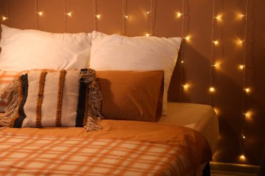 Geceleri yatak odasında yumuşak yastıklı ve parlayan ışıklar olan büyük bir yatak.