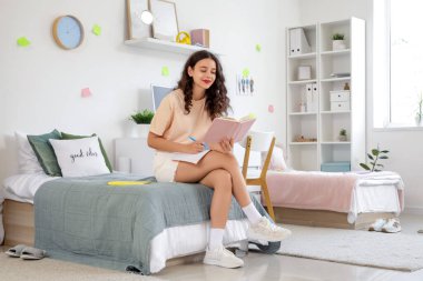 Yurt odasında kitap okuyan kız öğrenci.