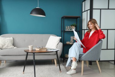 Evdeki koltukta oturan gazeteli genç ve güzel bir kadın.