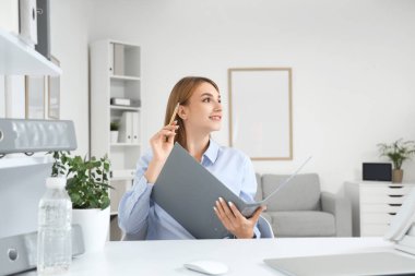 Ofiste çalışan, evrak klasörlü genç bir iş kadını.