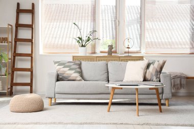 Tahta merdiveni, kanepesi ve masası olan aydınlık oturma odasının içinde.