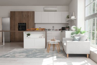 Modern bir stüdyo daire mutfak tezgahı, şık bir kanepe ve pencere kenarındaki masa.