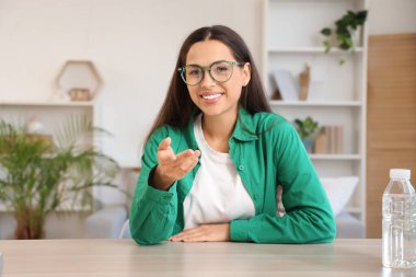 Gözlüklü güzel bir kadın evde görüntülü sohbet ediyor.