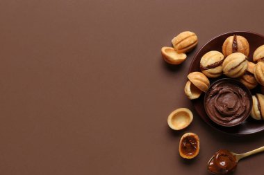 Kahverengi arka planda kaynamış yoğunlaştırılmış sütle ceviz şeklinde kurabiyeler.