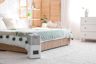 Yatak odasının içinde tuvalet, katlama ekranı ve yatağın yanında modern nemlendirici var.