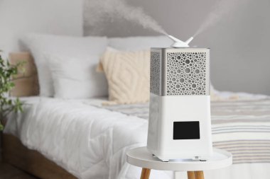 Yatak odasının yanındaki taburede modern nemlendirici.