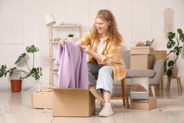 Evde yeni kapüşonlu paketleri açan genç bir kadın.