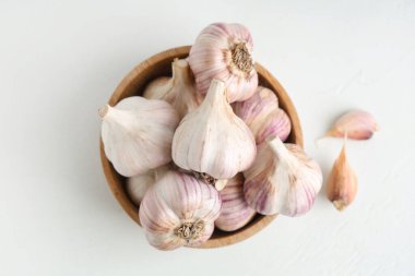 Taze sarımsaklı ahşap kase ve beyaz arka planda karanfil.