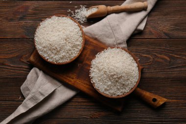 Ahşap zemin üzerinde çiğ pirinç dolu kâseler ve kepçeler.