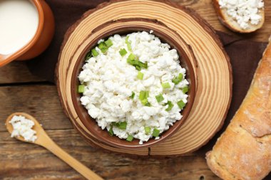 Bir kase taze süzme peynirli ekmek ve tahtadan arka planda sütle.