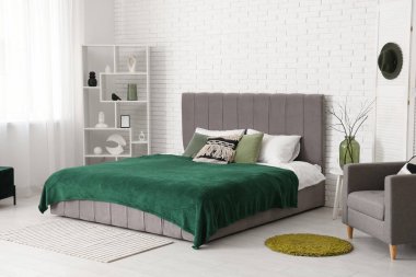 Yatak odasının içi, rahat yatak odası ve beyaz tuğla duvarın yanındaki raf ünitesi.